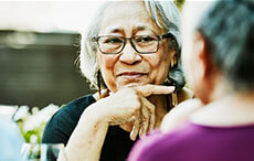 Smiling senior woman in discussion with family during outdoor dinner party
